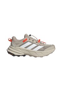 Chaussure de trail Adidas Terrex beige avec des bandes blanches, un onglet de traction orange et des accents, semelle épaisse et semelle extérieure en caoutchouc Continental.