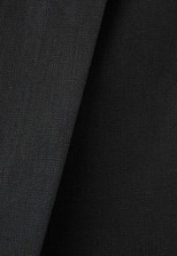Gros plan de couches de tissu tissé gris foncé et noir montrant la texture et les détails subtils des plis.