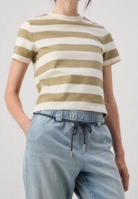 Olivgrön och vit randig bomullströja med rund hals och korta ärmar, ihopparad med ljusblå byxor med dragsko.