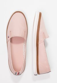 Zapatillas rosas rubor con paneles laterales elásticos, detalles en marrón y suelas de goma blancas. Interior texturizado y detalle del logo en el talón.