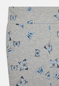 Γκρι ύφασμα με επαναλαμβανόμενο σχέδιο από μπλε πεταλούδες, που ποικίλλουν σε μέγεθος και σχέδιο, σε μαλακό, υφασμένο υλικό.