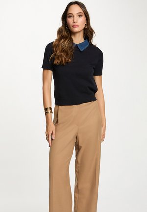 Suéter de manga corta en navy con un collar de mezclilla, combinado con pantalones de pierna ancha en color beige. Textura suave y diseño ajustado. Estilo minimalista.