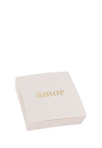 Biały kwadratowy pudełko z zaokrąglonymi krawędziami, na wieczku ze złotymi literami wyśrodkowanymi słowo "amor".