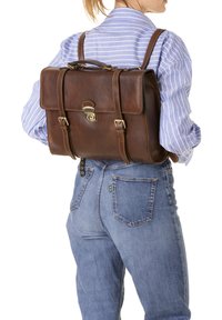 Sac à dos en cuir brun avec un rabat, quincaillerie en métal et bretelles réglables. Surface texturée et forme rectangulaire classique.