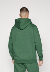 Felpa verde realizzata in tessuto morbido con cappuccio con cordino, polsini a costine e orlo. Design semplice e senza cuciture con una texture che appare leggermente melangiata.