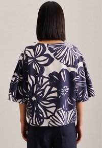 Blusa navy con stampa floreale, maniche ampie e vestibilità rilassata. Realizzata in cotone, presenta grandi motivi floreali bianchi sul retro.