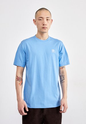 T-shirt di cotone azzurro chiaro con collo rotondo e maniche corte. Presenta un piccolo logo Adidas bianco sul petto sinistro. Design semplice.