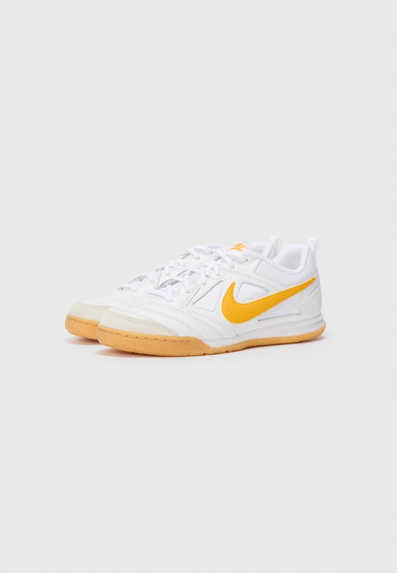 Zapatillas deportivas blancas con acentos amarillos, de material sintético y malla, de perfil bajo, diseño con cordones y suela de goma.