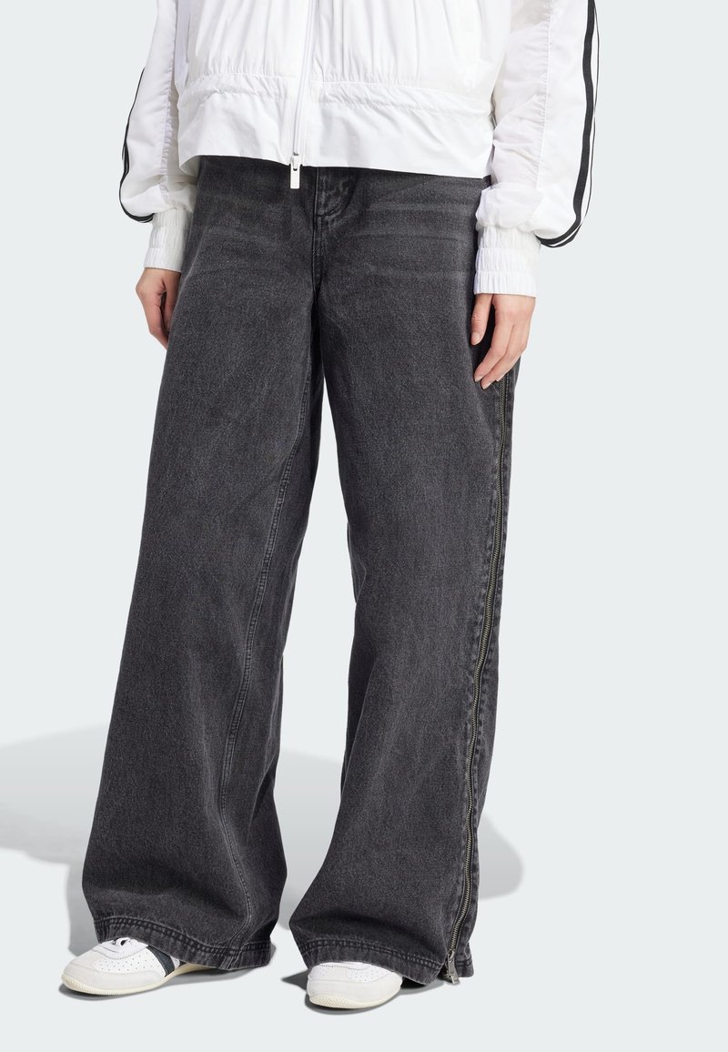 Videbukser i mørkegrå denim med teksturfinish, med sidelukning og kombinert med hvite joggesko.