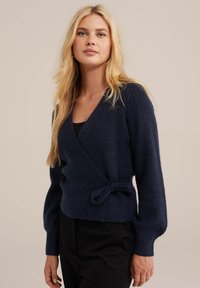 Temno modra zavita jopica iz mehkega teksturiranega materiala z dolgimi rokavi in poudarjenim pasom, ki ima globok V-izrez.