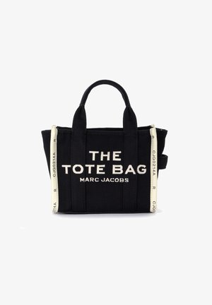 Geantă de tote din pânză neagră cu text alb care citește „THE TOTE BAG MARC JACOBS.” Are mânere scurte și accente albe contrastante.