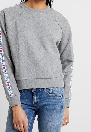 Sweatshirt gris avec des manches raglan, des poignets et un ourlet en bords-côtes. Les bandes latérales présentent un texte rouge et bleu "J ❤️ MES VANS". Matière douce en mélange de coton.