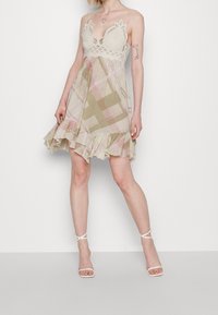 Kevyt, ruudullinen mekko pastelliväreissä, jossa on pitsinen yläosa, säädettävät olkaimet ja röyhelöhelma.