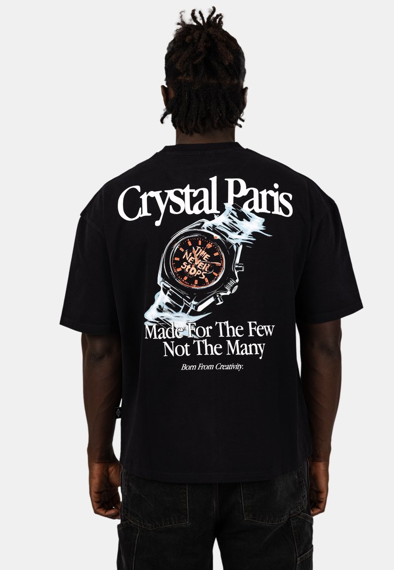Černé bavlněné tričko s potiskem hodinek a textem "Čas nikdy nezastavuje" a "Crystal Paris" v tučném bílém písmu na zadní straně.