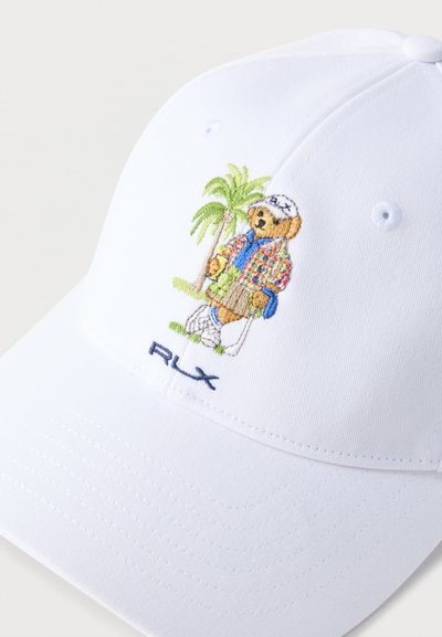 Gorra blanca con un oso de peluche bordado con ropa de golf, de pie junto a una palmera, sosteniendo un palo de golf, y el logo "RLX" abajo.