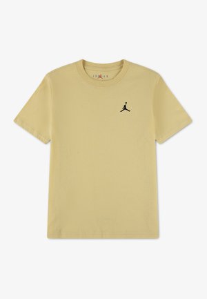 Beżowy T-shirt z krótkim rękawem i okrągłym dekoltem, z czarnym logo Jumpman na lewej piersi, minimalistyczny design, ułożony na płasko na białym tle.