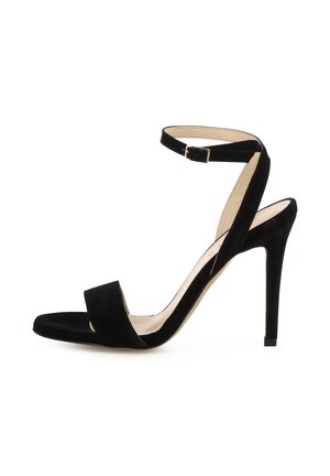 Schwarze Wildleder-Sandalette mit Absatz, Knöchelriemen und Schnalle, offenem Zehenbereich und schlankem Stiletto-Absatz auf weißem Hintergrund.