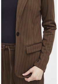 Brun rutig blazer med en enda knapp, texturerad tyg och detalj med sidoficka, kombinerad med matchande byxor med dragsko.