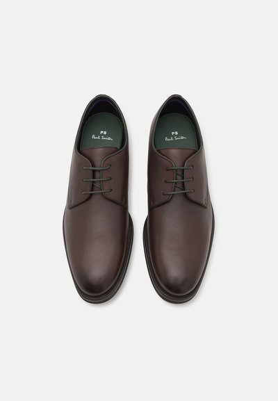 Chaussures en cuir marron avec une finition lisse, dotées de lacets verts et d'un bout arrondi. L'intérieur comporte une semelle verte avec le logo "PS Paul Smith".