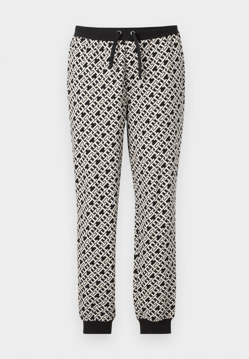 Schwarz-weiße Jogginghosen mit geometrischem Muster, elastischem Bund und gerippten Bündchen. Das Material wirkt weich und leicht texturiert.