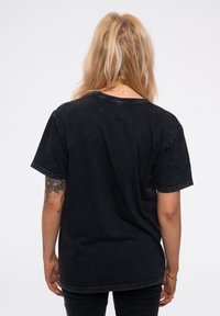 Black oversized t-shirt with a soft, textured fabric, featuring a crew neckline and short sleeves. Minimalist style with distressed details.