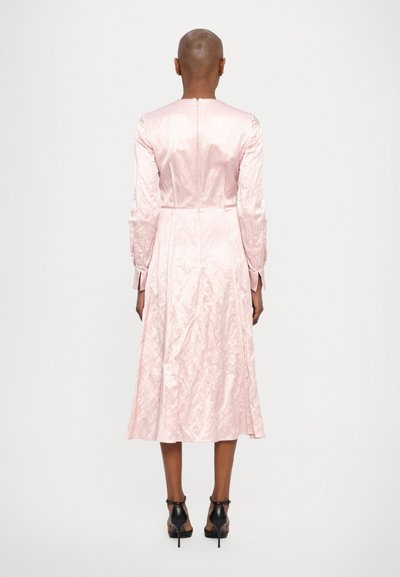 Long pink satin dress with a smooth texture, full sleeves, and a flared silhouette, featuring a subtle sheen and back zipper closure.