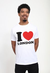 Bílá bavlněná tričko s velkým černým "I", červeným srdcem a tučným černým textem "LONDON". Krátké rukávy, kulatý výstřih a volný střih.