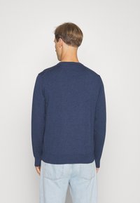Suéter tricotado azul-marinho com mangas longas e decote redondo. Apresenta punhos e bainha canelados. Textura suave, design simples.