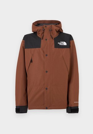 Brun hettejakke med glidelås, svart øvre del, justerbar hette og logo på brystet. Har trykknapper og elastiske ermekanter.