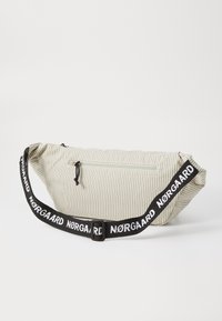 Poche banane rayée dans des couleurs claires avec une poche zippée, une sangle noire ajustable arborant le nom de la marque en blanc, et une forme élancée.