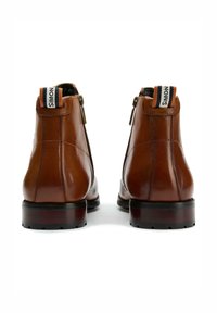 Brown leather ankle boots with a smooth texture, round toe, and zip closure. Features a contrasting heel and a branded pull tab at the back.