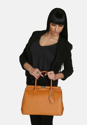 Handtasche aus braunem Leder mit strukturierter Form, oberen Griffen und metallischen Akzenten. Sie verfügt über eine strukturierte Oberfläche und einen Anhänger, der seitlich hängt.