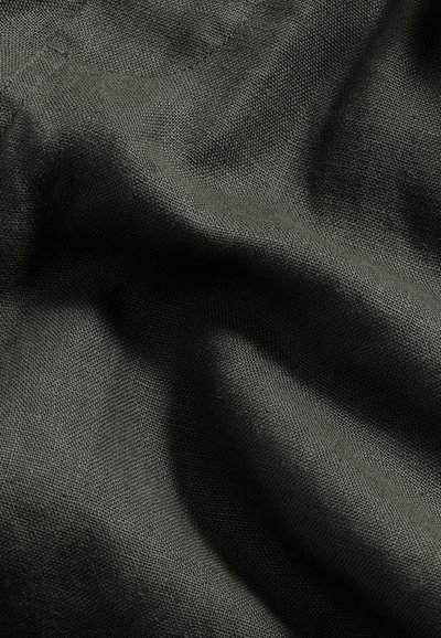 Tissu gris foncé avec une texture tissée visible, montrant des plis doux et des ombres créant une surface légèrement froissée.