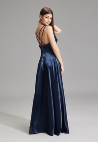 Lungo abito in satin blu navy con un corpino aderente, spalline incrociate sul retro e una gonna fluente. Texture liscia e una leggera lucentezza.