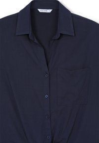 Chemise bleu marine à boutons avec col, poche poitrine unique et tissu texturé. Dotée de boutons assortis le long du devant.