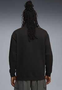 Felpa nera con collo alto e maniche lunghe, realizzata in un materiale morbido. Presenta una vestibilità comoda e polsini a coste.