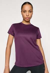 Lühikeste varrukatega sportlik pluus sügavlillades toonides, millel on ümar kaelus ja sile pind. Disainis on peened õmblused ja kumer alumine äär.