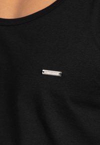 T-shirt in cotone nero con un'etichetta metallica argento con il testo "SMILOBX" nella zona sinistra del petto. Tessuto morbido e scollatura rotonda.