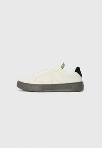 Fehér sneaker texturált szürke talppal, diszkrét logo részlettel, lapos fűzővel és fekete sarok akcentussal. Simító bőr felsőrész paneles kialakítással.