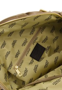 Beige håndtaske interiør med en glat stofforing og gentaget "VENEZIA" branding. Inkluderer en lynlåslomme og guldlås hardware.