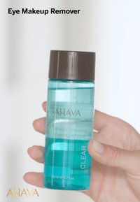Transparent flaska med ögonmakeupborttagning med ett brunt lock, märkt "AHAVA" och "Time to Clear", som rymmer 125 ml (4,2 fl. oz).