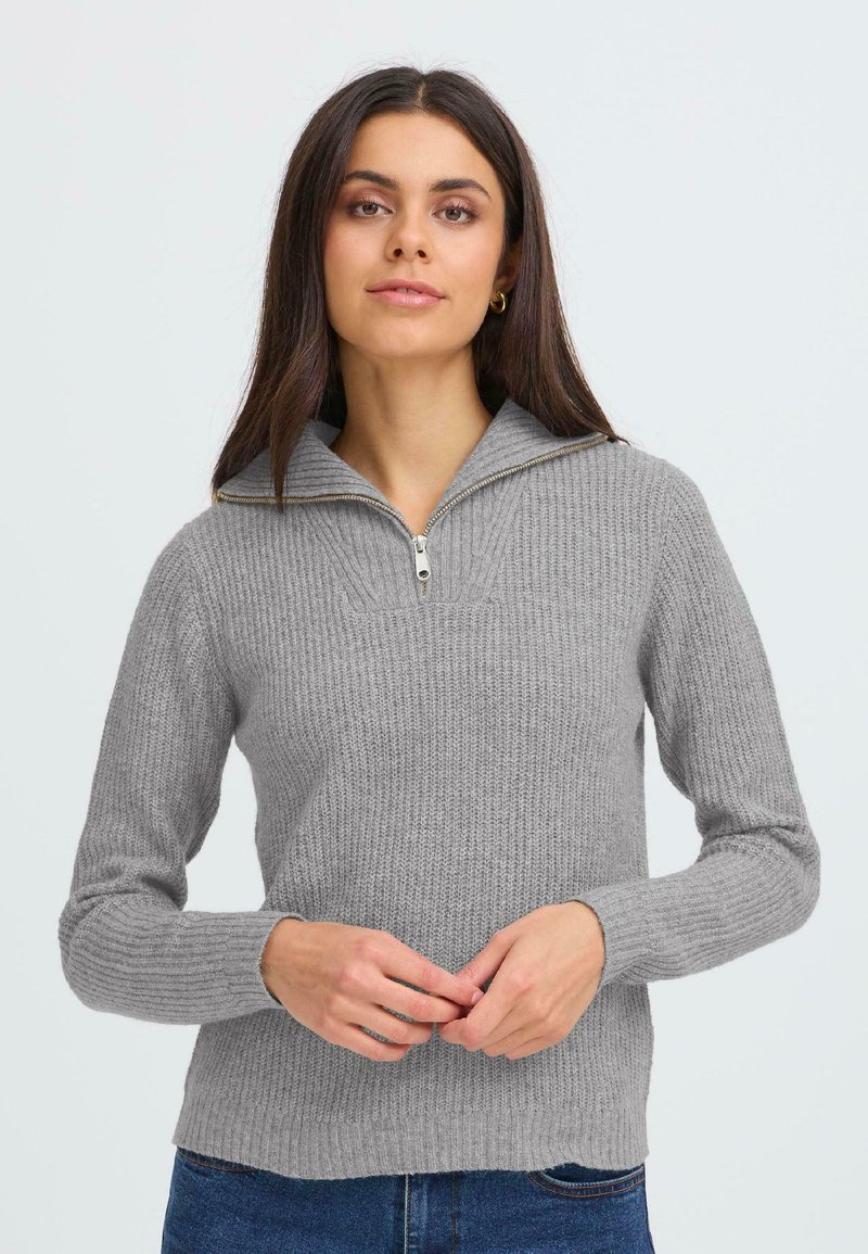 Grå ribbet striktrøje med halv lynlås krave, der har lange ærmer og en struktureret overflade. Stoffet ser blødt og varmt ud.