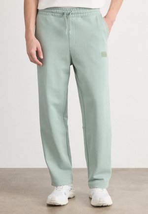 Pantaloni della tuta verde menta realizzati in materiale morbido, con cintura elastica dotata di cordino e tasche laterali. Branding minimale sulla gamba.