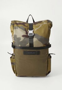 Zaino con motivo mimetico nei toni del verde e marrone, con design a risvolto superiore, tracolla regolabile e patch con logo frontale.