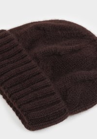 Brązowa dziana czapka beanie wykonana z miękkiej wełny, z prążkowanym mankietem i luźnym krojem. Teksturowana powierzchnia o lekko puszystym wyglądzie.