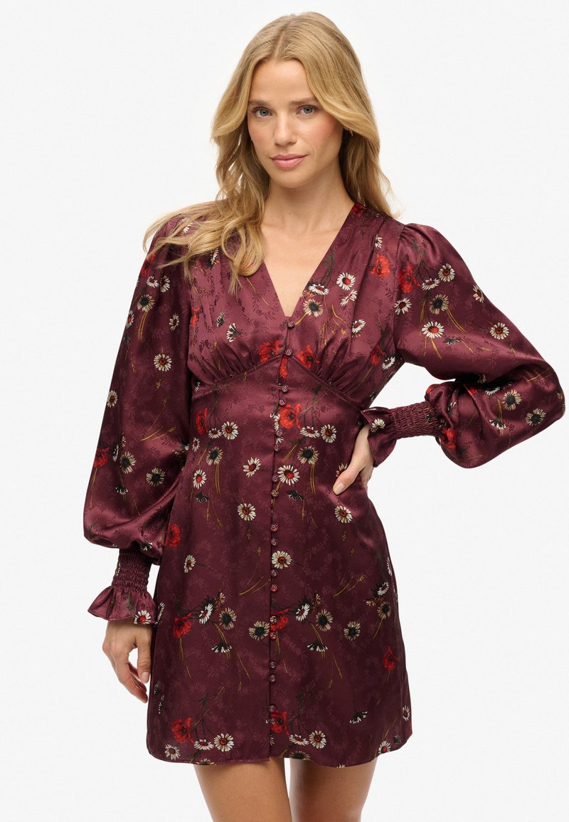 Vestido de satén burdeos con patrón floral, escote en V profundo, mangas abullonadas y frente con botones. Tejido texturizado con puños y dobladillo fruncidos.