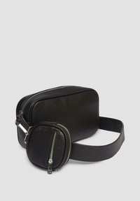 Schwarze Leder-Crossbody-Tasche mit einer strukturierten Oberfläche, ausgestattet mit einem Hauptfach und einem abnehmbaren runden Beutel, beide mit silbernen Reißverschlüssen.