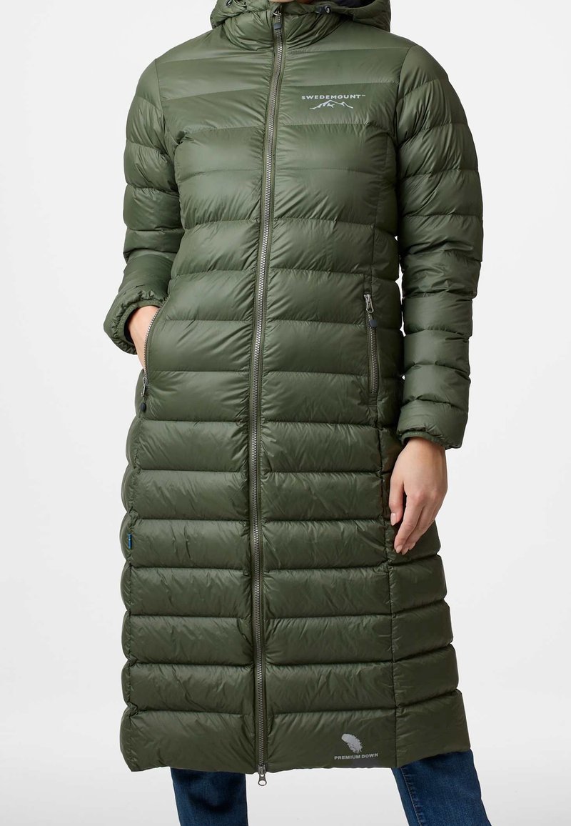 Zelený prošívaný kabát s kapucí, se zvlněným vzorem, bočními kapsami a logem na hrudi. Zapínání na zip s prodlouženou délkou.