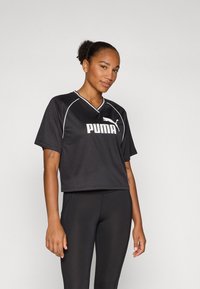 Crop top noir à manches courtes en tissu respirant, avec un col en V, des liserés blancs et un logo Puma blanc bien visible sur la poitrine.
