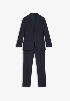 Completo blu navy con vestibilità su misura, fodera strutturata, giacca monopetto e pantaloni a pinces piatti. Presenta due tasche frontali e dettagli con bottoni.